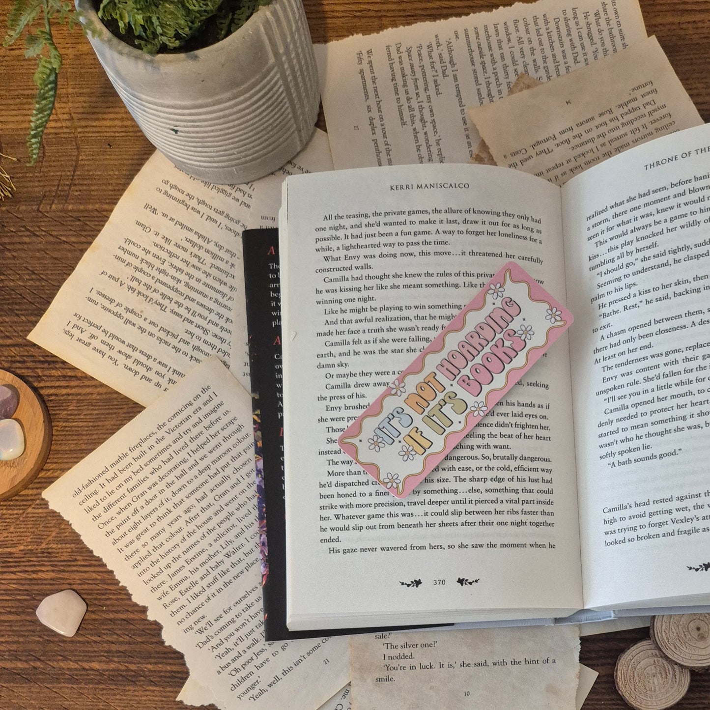 Its nor hoarding if it's books bookmark. The bookmakr is placed intop an open book surrpunded by a fake plant, a collection of crystals and ripped and aged book pages