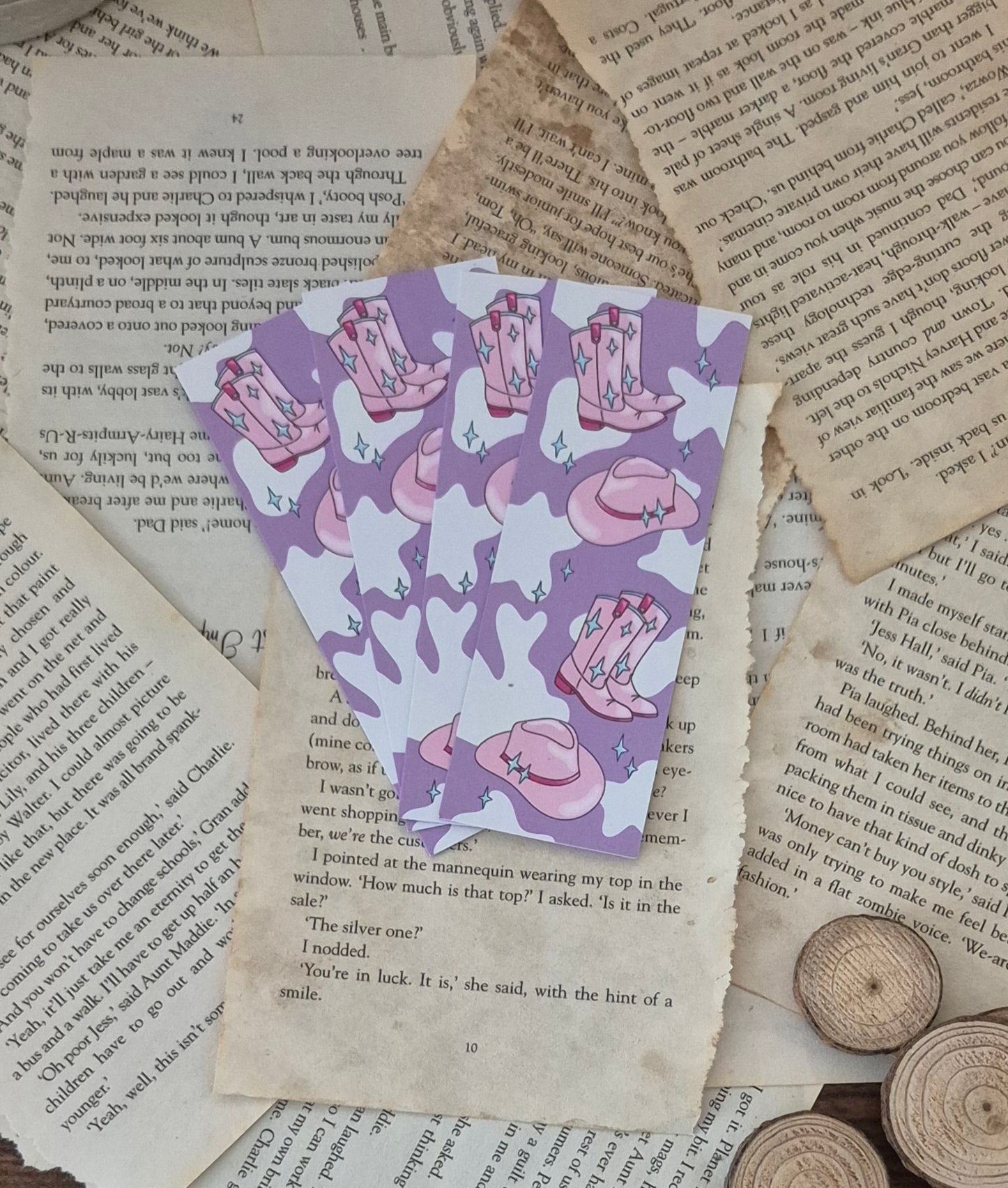 A fan of cowboy trope bookmarks sre spread out ontop a bed of ripped and aged book pages 