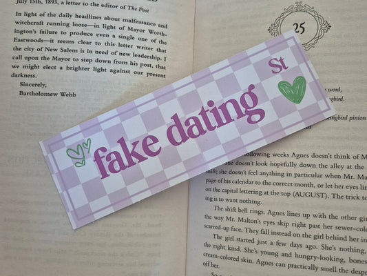 Chequered bookmark with the words 'fake dating street' placed on an open book