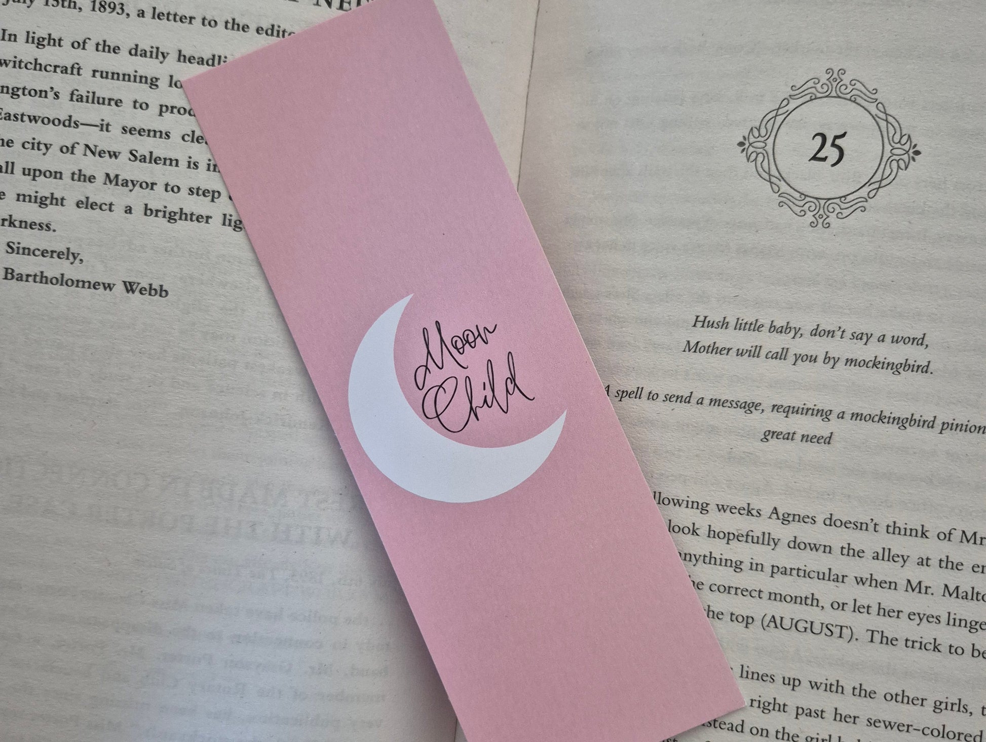 Pink bookmark with 'Moon Child' design on a book page