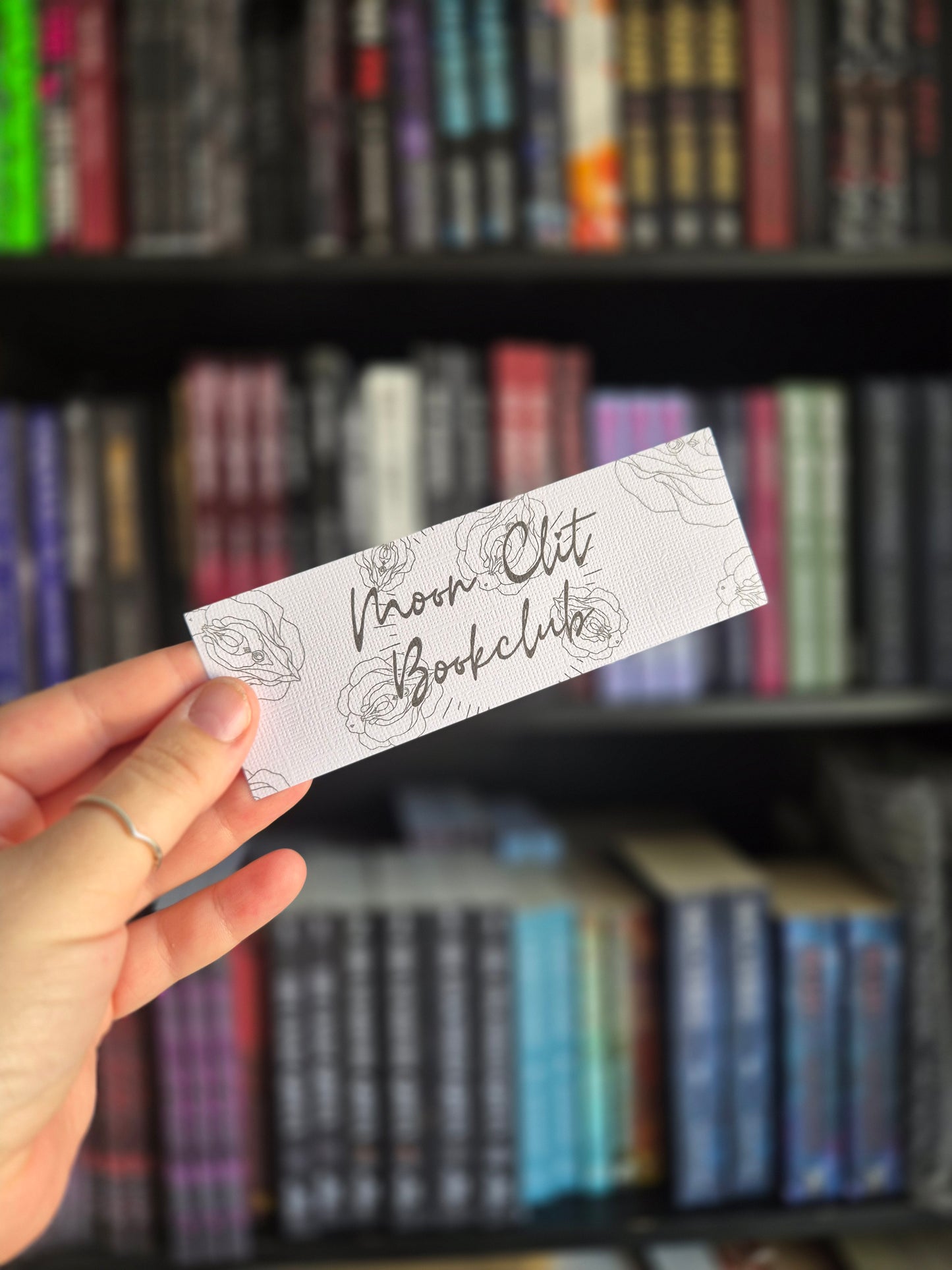 Colour your own bookmark with the phrase 'moonclit bookclub' surrounded with flowers