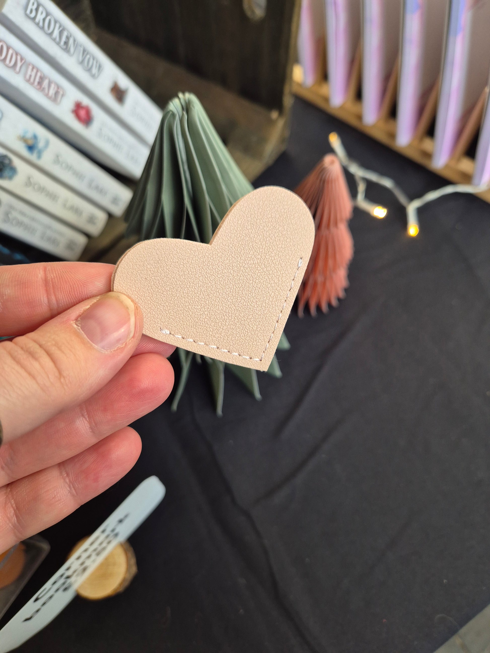 Heart-shaped beige corner bookmark held by a hand with a blurred background